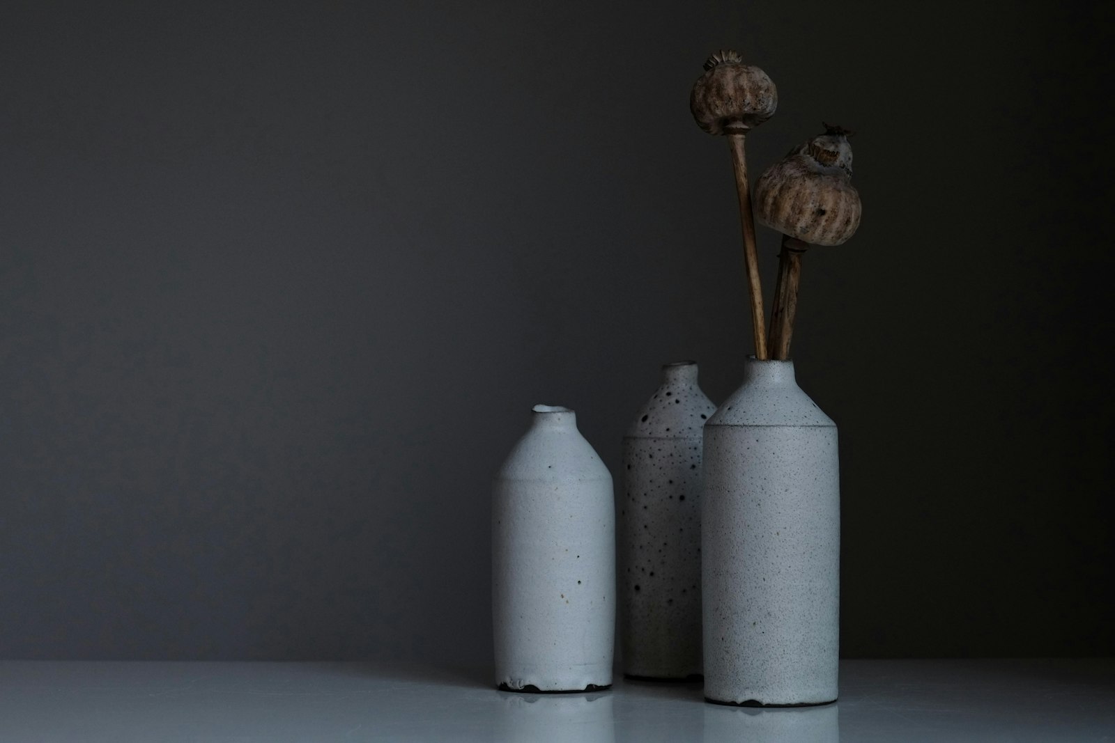 Trzy ceramiczne butle z makówkami na stole